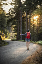 Female hitchhiker on a road, Col de Vergio, Corsica, France - MSUF00033