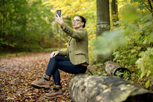 Reife Frau nimmt ein Selfie in einem Herbstwald - FLLF00353