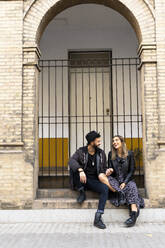 Laughing young couple sitting on stairs outdoors - ERRF02153