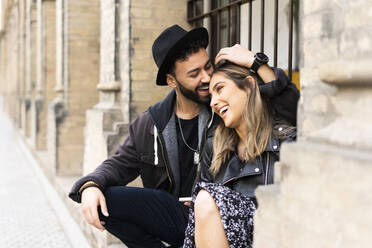 Young couple sitting outdoors having fun - ERRF02155