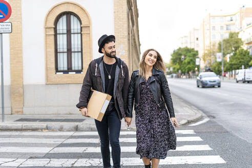 Porträt eines glücklichen jungen Paares beim Überqueren der Straße - ERRF02160