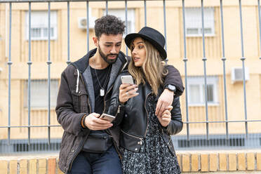 Junges Paar in der Stadt beim Telefonieren mit dem Handy - ERRF02166
