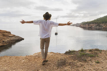 Rückenansicht eines glücklichen jungen Mannes vor dem Meer, Ibiza, Balearische Inseln, Spanien - AFVF04249