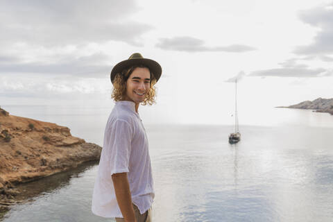 Porträt eines entspannten jungen Mannes vor dem Meer, Ibiza, Balearische Inseln, Spanien, lizenzfreies Stockfoto