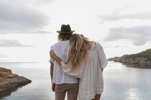 Back view of young couple in love standing in front of the sea, Ibiza, Balearic Islands, Spain - AFVF04255