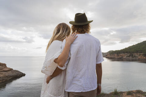 Rückenansicht eines jungen Paares vor dem Meer mit Blick auf die Aussicht, Ibiza, Balearische Inseln, Spanien, lizenzfreies Stockfoto