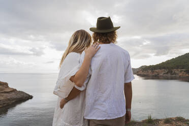 Rückenansicht eines jungen Paares vor dem Meer mit Blick auf die Aussicht, Ibiza, Balearische Inseln, Spanien - AFVF04260