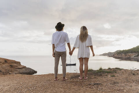 Rückenansicht eines jungen verliebten Paares vor dem Meer, Ibiza, Balearen, Spanien, lizenzfreies Stockfoto