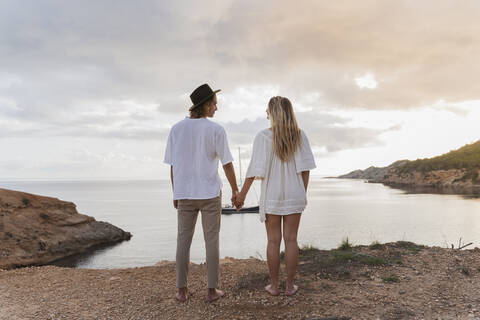 Back view of young couple in love standing in front of the sea, Ibiza, Balearic Islands, Spain stock photo