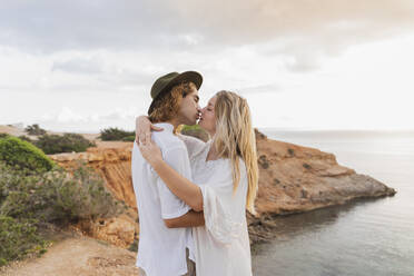 Kissing young couple in love in front of the sea, Ibiza, Balearic Islands, Spain - AFVF04270