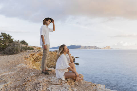 Junges Paar vor dem Meer mit Blick in die Ferne, Ibiza, Balearische Inseln, Spanien, lizenzfreies Stockfoto