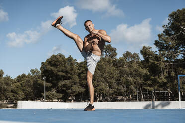 Portrait of barechested muscular man practicing fitness exercises outdoors - RCPF00132