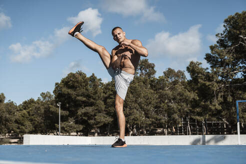 Porträt eines muskulösen Mannes mit nacktem Oberkörper, der Fitnessübungen im Freien macht - RCPF00132