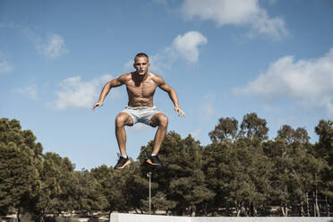 Portrait of barechested muscular man jumping outdoors - RCPF00133