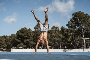 Barechested muscular man doing a handstand outdoors - RCPF00134