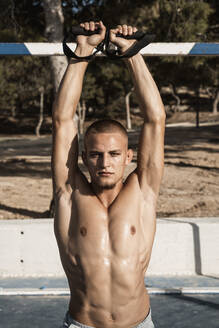 Portrait of barechested muscular man practicing fitness exercises outdoors - RCPF00144