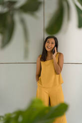 Porträt einer modischen, gelb gekleideten Frau, die telefoniert - MAUF03107