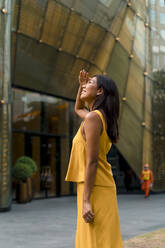 Portrait of fashionable woman dressed in yellow looking up - MAUF03111