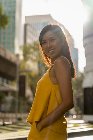Porträt einer modischen, gelb gekleideten Frau, die im Gegenlicht steht, lizenzfreies Stockfoto