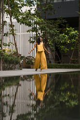 Modische Frau in gelb gekleidet tanzen in der Stadt - MAUF03126