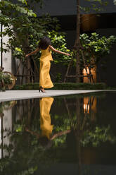 Rückenansicht einer modischen, gelb gekleideten Frau beim Tanzen in der Stadt - MAUF03128
