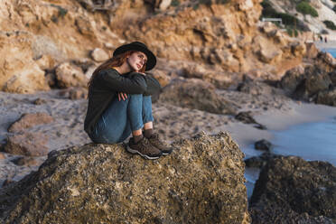 Junge Frau sitzt am Strand und genießt den Sonnenuntergang, Ibiza - AFVF04296