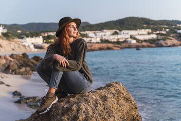 Junge Frau sitzt am Strand und genießt den Sonnenuntergang, Ibiza - AFVF04297