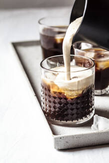 Frothed milk is poured over iced coffee - SBDF04115