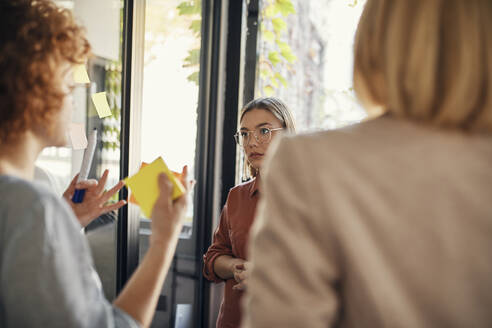 Colleagues with sticky notes discussing in office - ZEDF02731