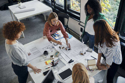 Businesswomen having a meeting in office with wind turbine models on table - ZEDF02766