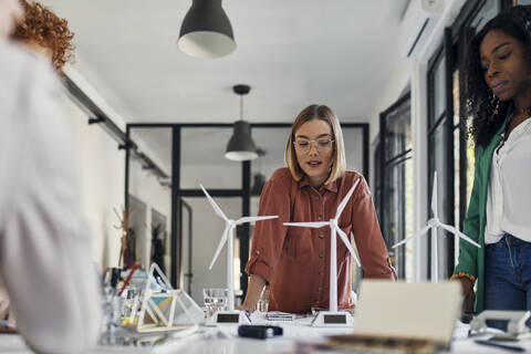 Businesswomen having a meeting in office with wind turbine models on table stock photo