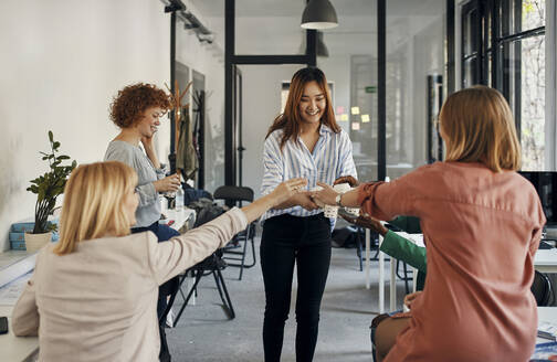 Businesswoman serving coffee to colleagues in office - ZEDF02773