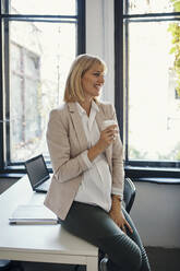 Pregnant businesswoman having a coffee break in office - ZEDF02787
