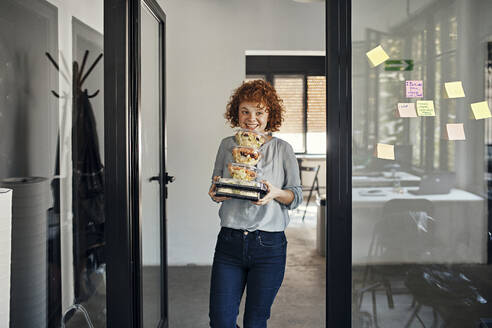 Smiling businesswoman serving takeaway food in office - ZEDF02794