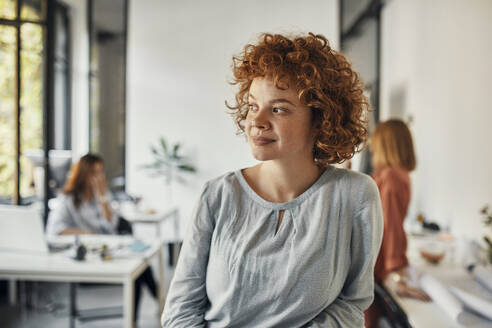 Porträt einer rothaarigen Geschäftsfrau im Büro mit Blick zur Seite - ZEDF02819