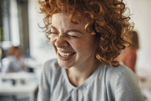 Porträt einer lachenden Geschäftsfrau mit geschlossenen Augen im Büro - ZEDF02821