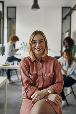 Portrait of a confident businesswoman in office with colleagues in background stock photo