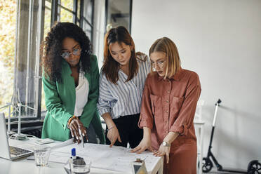 Businesswomen having a meeting in office with wind turbine models on table - ZEDF02836