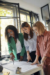 Geschäftsfrauen bei einer Besprechung im Büro mit Windradmodellen auf dem Tisch - ZEDF02837