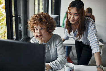 Two businesswomen looking at desktop pc in office - ZEDF02842