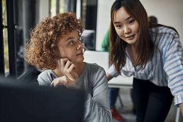 Zwei Geschäftsfrauen arbeiten zusammen am Schreibtisch im Büro - ZEDF02846