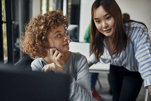 Two businesswomen working together at desk in office - ZEDF02846