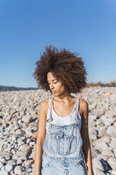 Porträt einer jungen Frau am leeren Strand, die nach oben schaut - AFVF04302