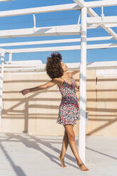 Young woman wearing summer dress enjoying the sunlight on a terrace - AFVF04321