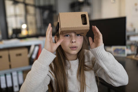 Mädchen mit VR-Brille aus Pappe im Büro, lizenzfreies Stockfoto