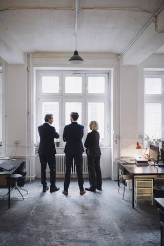 Geschäftsleute stehen am Fenster im Büro, lizenzfreies Stockfoto