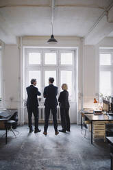 Business people standing at the window in office - GUSF02717