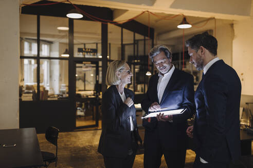 Geschäftsleute mit leuchtendem Tablet im Gespräch im Büro - GUSF02718