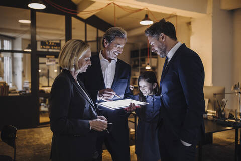 Geschäftsleute und Mädchen schauen auf leuchtende Tablet im Büro, lizenzfreies Stockfoto