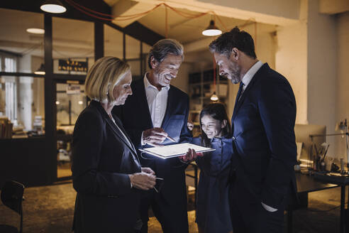 Business people and girl looking at shining tablet in office - GUSF02719